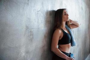 Leaning on the wall. Photo of gorgeous blonde woman in the gym at her weekend time