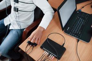 vista de partículas hombre sospechoso pasa detector de mentiras en la oficina. haciendo preguntas. prueba de polígrafo foto