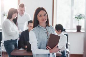 Stands in front of her colleagues. Group of people at business conference in modern classroom at daytime photo