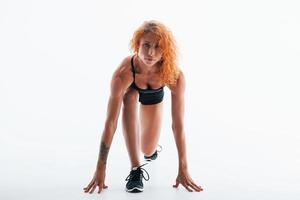 Having exercise. Redhead female bodybuilder is in the studio on white background photo