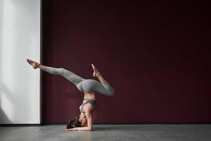 las piernas están arriba. chica con buen tipo de cuerpo físico tiene ejercicios en la habitación espacial foto