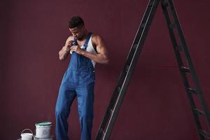 el uso de ropa. joven trabajador afroamericano con uniforme azul tiene trabajo que hacer foto