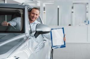 Always happy to see you. Manager sitting in modern white car with paper and documents in hands photo