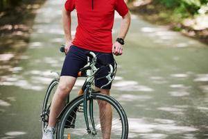 vista de partículas ciclista en bicicleta está en la carretera asfaltada en el bosque en un día soleado foto