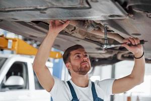 Fixing expensive car. Employee in the blue colored uniform works in the automobile salon photo