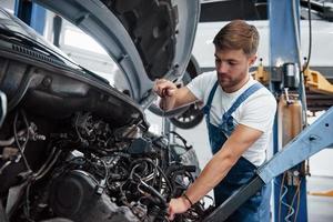 Pulling off metal rope. Employee in the blue colored uniform works in the automobile salon photo