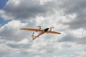 Modern small remote controlled white colored plane flying up in the sky photo