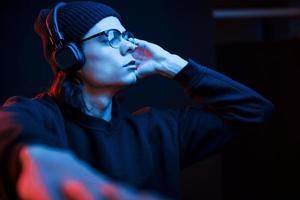 Tur it as loud as you can. Studio shot in dark studio with neon light. Portrait of serious man photo