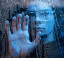 Blue color. Studio shot in dark studio with neon light. Portrait of serious man behind the wet glass photo