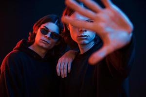 Stop gesture. Portrait of twin brothers. Studio shot in dark studio with neon light photo