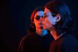 Colorful photo. Portrait of twin brothers. Studio shot in dark studio with neon light photo