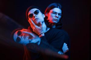 Illusion of three faces. Portrait of twin brothers. Studio shot in dark studio with neon light photo