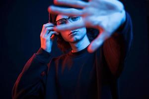 la mano izquierda está borrosa. foto de estudio en estudio oscuro con luz de neón. retrato de hombre serio