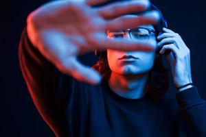 With elongated hand. Studio shot in dark studio with neon light. Portrait of serious man photo