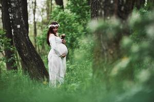 finalmente, es verano. hermosa mujer embarazada vestida da un paseo al aire libre. morena positiva foto