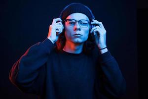 Listening to the music. Studio shot in dark studio with neon light. Portrait of serious man photo