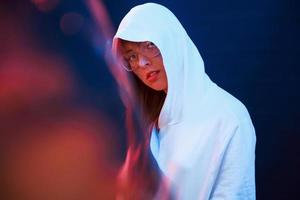 Looking at you with interest. Studio shot in dark studio with neon light. Portrait of young girl photo