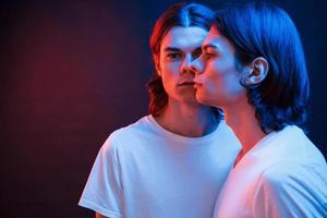 I'm getting double in my eyes. Portrait of twin brothers. Studio shot in dark studio with neon light photo