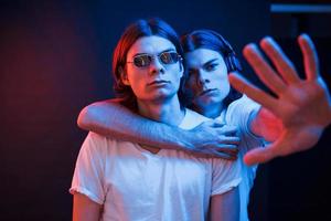 Our territory. Portrait of twin brothers. Studio shot in dark studio with neon light photo