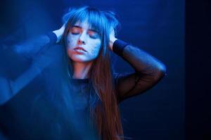 Gorgeous person. Studio shot in dark studio with neon light. Portrait of young girl photo