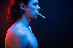 Good looking guy. Studio shot in dark studio with neon light. Portrait of serious man photo