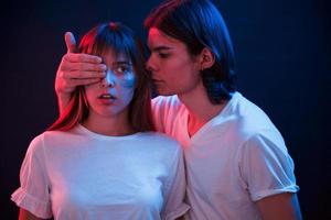 I have surprise for you. Couple standing in dark room with red and blue neon lighting photo