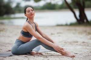 Lake behind. Brunette with nice body shape in sportive clothes have fitness day on a beach photo