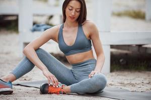 Brunette with nice body shape in sportive clothes have fitness day on a beach photo