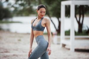 solo en el parque. morena con buena forma de cuerpo en ropa deportiva tiene un día de fitness en la playa foto