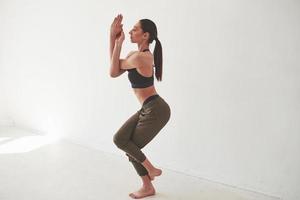 Yoga stand. Caucasian pretty woman against white background in the empty room photo