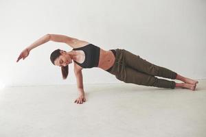 Fitness day. Caucasian pretty woman stands against white background in the empty room photo