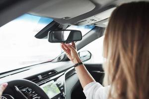 ajuste del espejo retrovisor. vista de cerca de las manos de la mujer en el hermoso y moderno coche de color negro foto