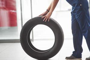 Side view. Woman walks with brand new wheel to the car. Conception of repair photo