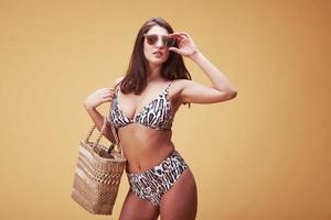 On vacation. Stylish beautiful young girl in bikini stands and posing in the studio photo