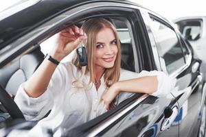 esto es mio ahora hermosa chica rubia sentada en el auto nuevo con interior negro moderno foto