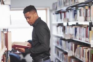 Good natural lighting. African american man in the library searching for some information in the books photo