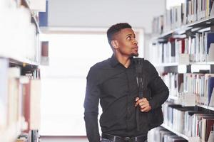 Going forward with backpack. African american man in the library searching for some books photo