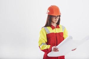 plan de trabajo. mujer morena con uniforme naranja y amarillo se alza contra fondo blanco en el estudio foto