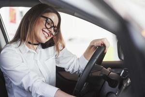 placer hablar con usted. mujer con ropa oficial probando su auto nuevo en el salón del automóvil foto