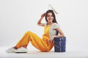 Make it easy. Brunette woman in yellow uniform sits against white background in the studio photo