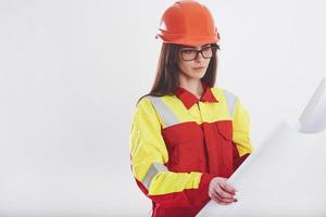 What kind of work do we have today. Brunette woman in orange and yellow uniform stands against white background in the studio photo