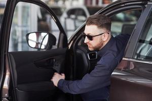 How it feels. Man in official clothes trying his new car in automobile salon photo