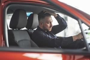 Modern haircut. Man in official clothes trying his new car in automobile salon photo