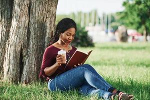 Coffee in hand. Cheerful african american woman in the park at summertime photo