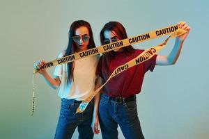 Colorful lighting. Studio shot indoors with neon light. Photo of two beautiful twins