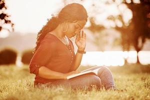 Amazing sunlight. Cheerful african american woman in the park at summertime photo