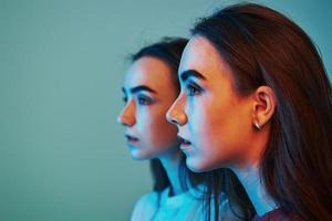 Conception of futurism. Studio shot indoors with neon light. Photo of two beautiful twins