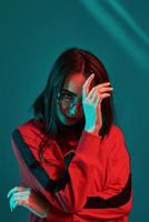 Careful looks at you. Studio shot indoors with neon light. Portrait of beautiful young girl photo