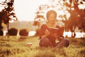 Pleasure to learn some new stuff there. Cheerful african american woman in the park at summertime photo