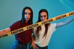 Creative people. Studio shot indoors with neon light. Photo of two beautiful twins